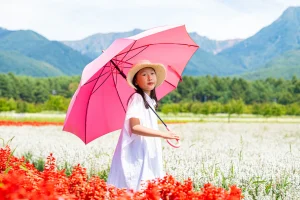 ピンクの傘を差して花畑を歩く9歳の娘